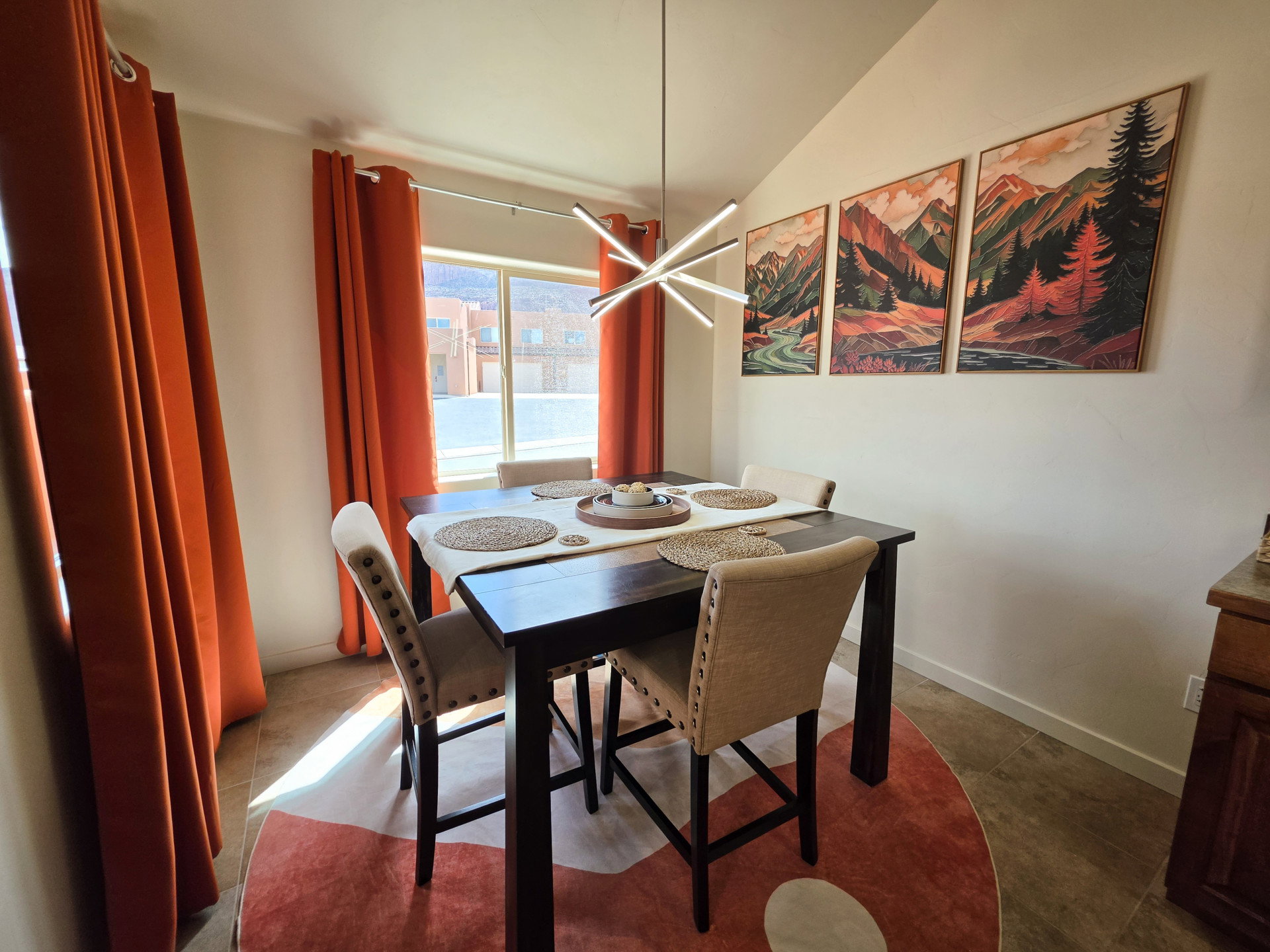 Bright dining area featuring a vaulted ceiling and a modern linear pendant light fixture