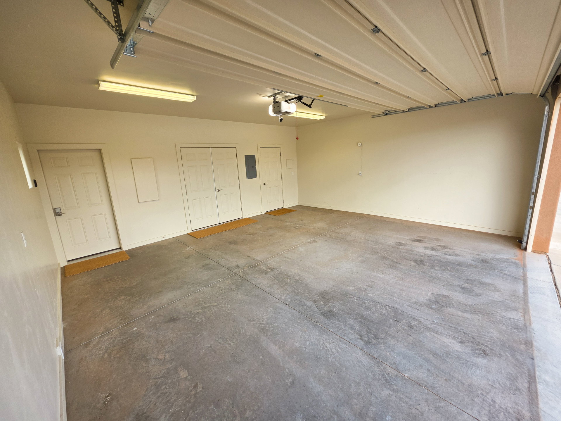 Spacious garage featuring a concrete floor, painted walls, and overhead lighting