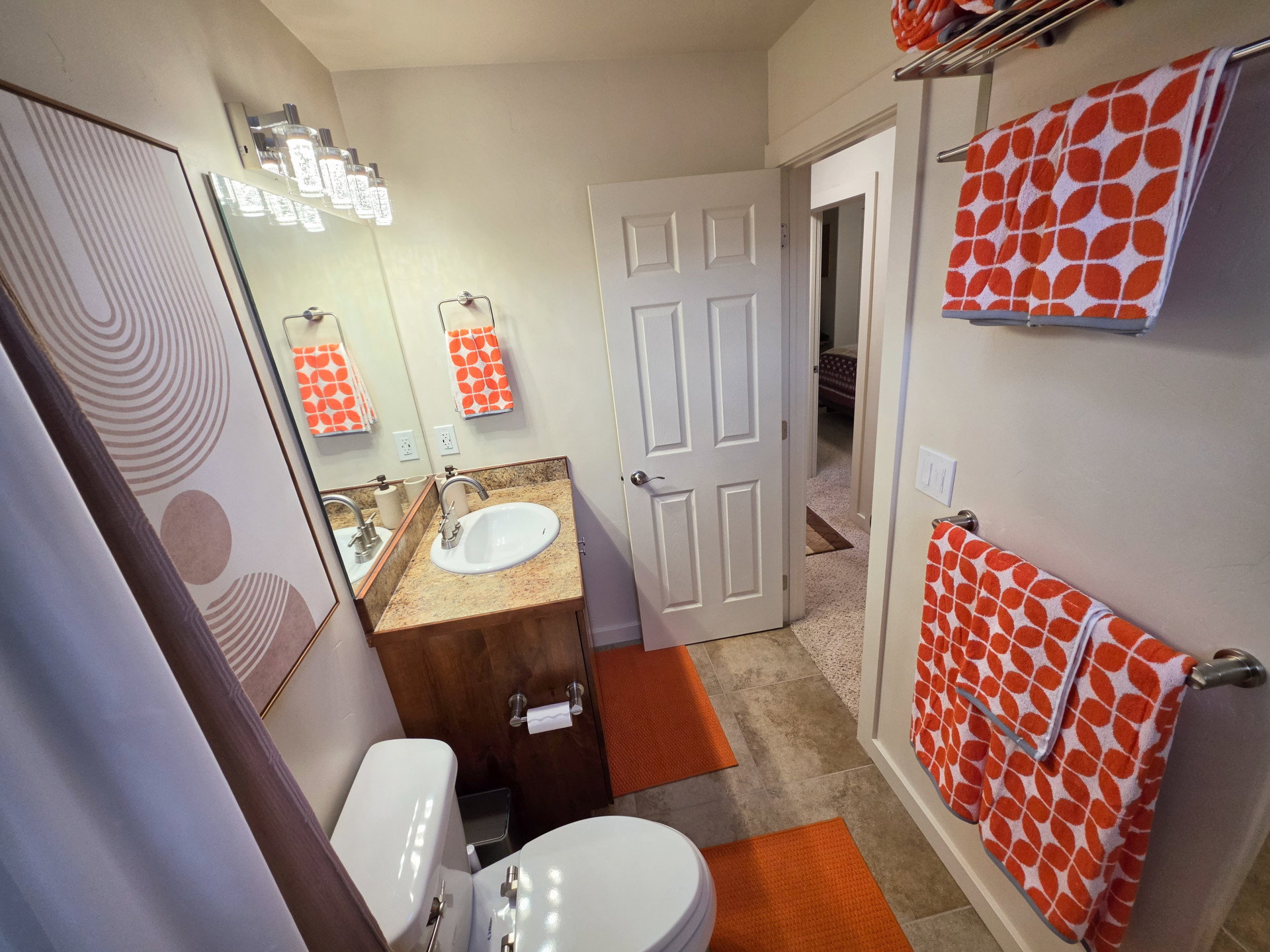 Bathroom featuring a vanity with a light-toned countertop and an integrated sink, a large mirror, and a multi-bulb light fixture