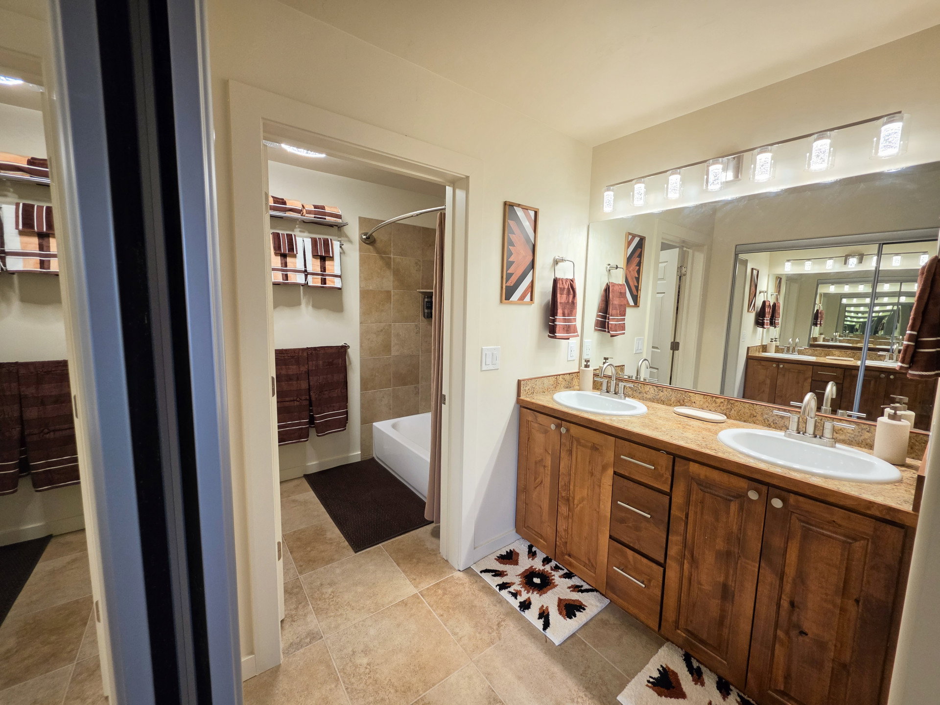 Dual vanity featuring wood-finish cabinetry, integrated sinks, and a stone-finish countertop