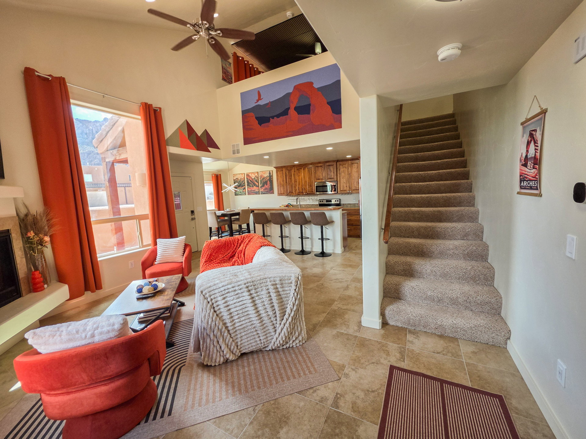 Living area with a fireplace with raised hearth, a ceiling fan, and vaulted ceiling