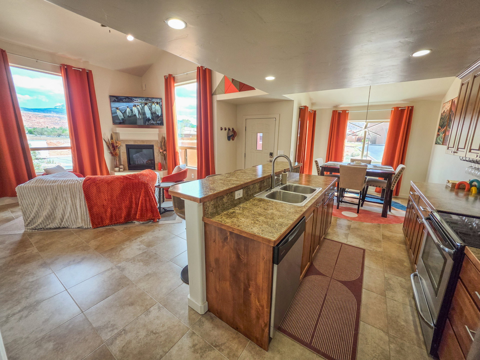 Kitchen featuring a kitchen island with sink, a breakfast bar, stainless steel appliances, open floor plan, and a glass covered fireplace