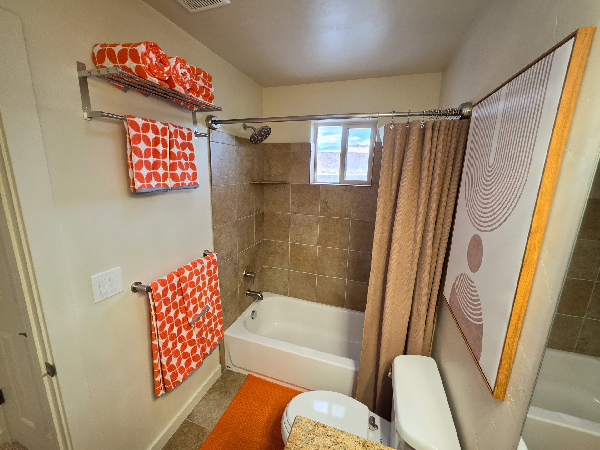 Bathroom featuring a built-in tub with tile surround, a window, and a toilet