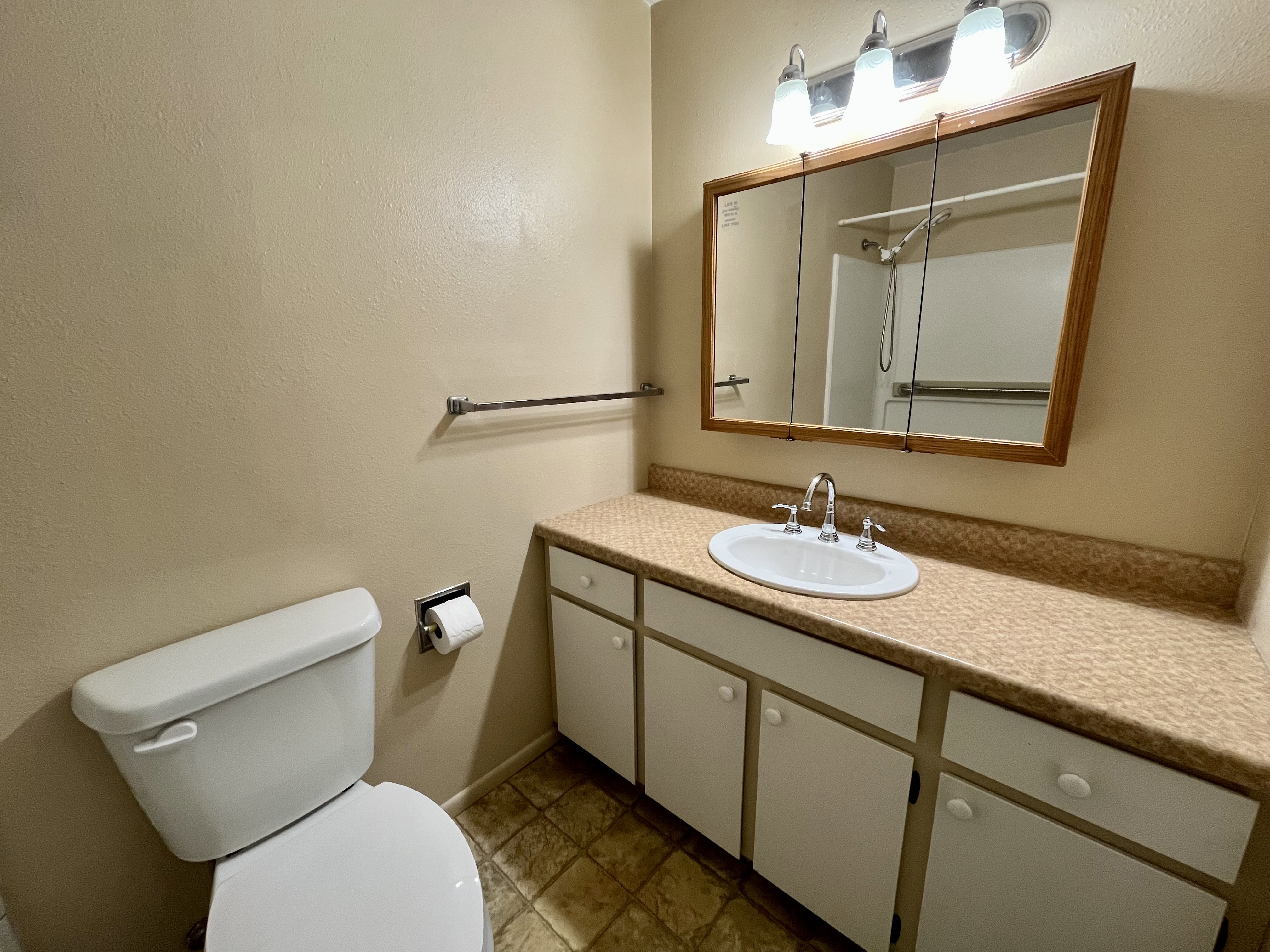 Bathroom with vanity, a shower, and a textured wall