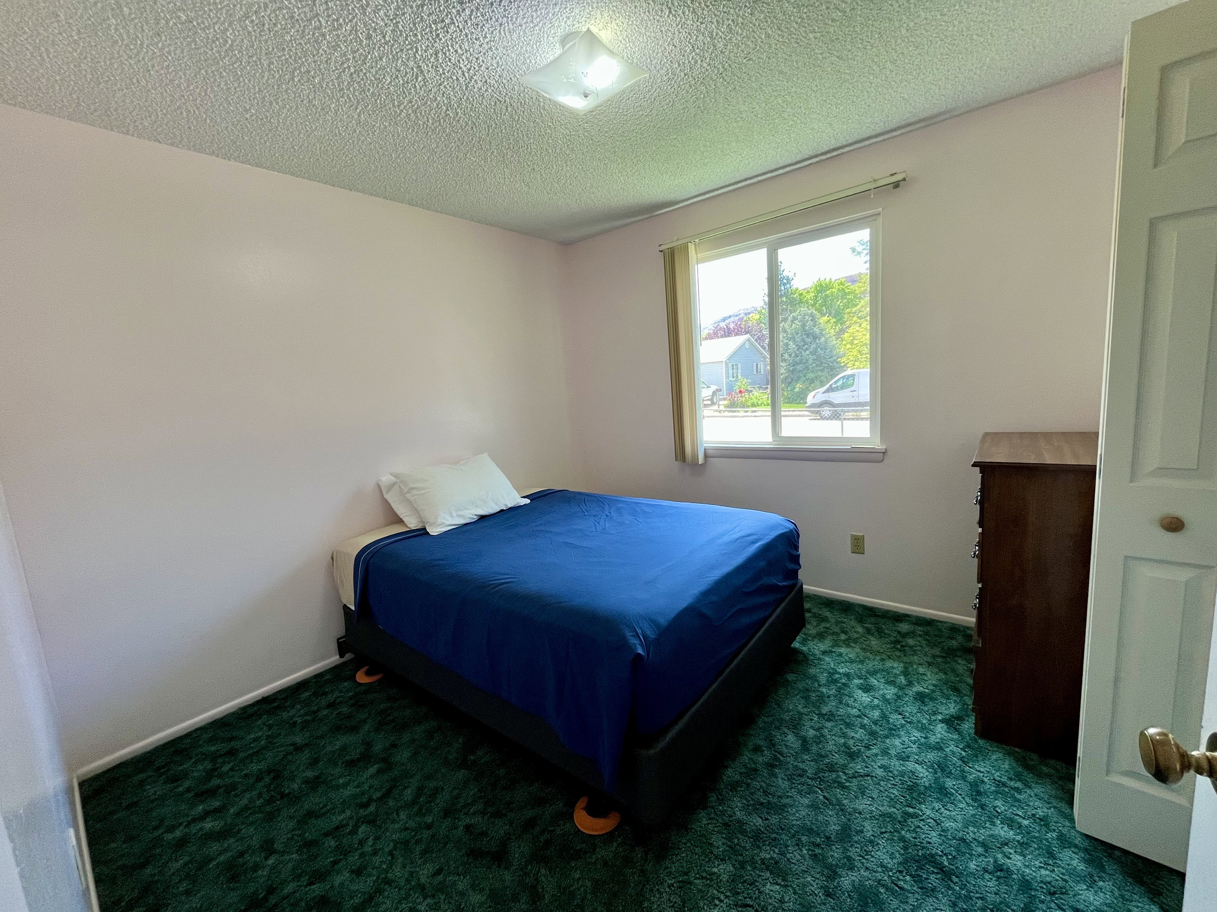 Bedroom with dark carpet and a textured ceiling