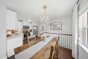 Dining space with a chandelier and dark wood-style flooring