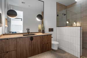 Bathroom featuring light aggregate flooring, vanity, and a walk in shower