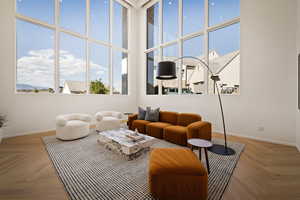 Living area featuring parquet flooring, a high ceiling, and healthy amount of natural light