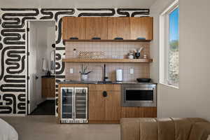 Bar featuring wood finish cabinets, wine cooler, backsplash, open shelves, and stainless steel microwave