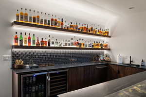 Indoor wet bar featuring modern cabinets, dark wood finish cabinetry, open shelves, and tasteful backsplash
