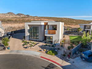 Modern home with a mountain view, brick siding, stucco siding, and concrete driveway