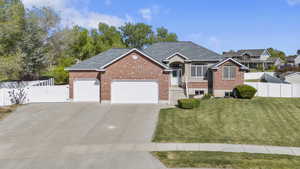 View of front of house featuring an attached garage, brick siding, concrete driveway, and a gate