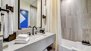 Bathroom with shower / bath combo with shower curtain and vanity
