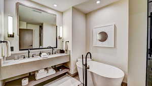 Full bathroom featuring double vanity, a freestanding tub, and recessed lighting