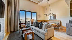 Living area featuring a high ceiling, light wood-type flooring, and a glass covered fireplace