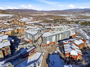 Snowy aerial view featuring a mountain view and a view of apartment building / complex