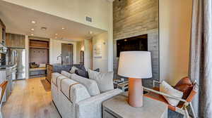 Living room featuring light wood finished floors, recessed lighting, and a high ceiling
