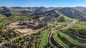 Aerial view of property's location featuring a mountain backdrop and a local golf course