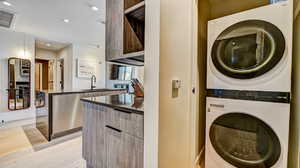 Laundry area featuring stacked washer and dryer, light wood finished floors, and recessed lighting