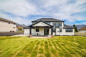 Back of house featuring a mountain view, board and batten siding, a patio, and a yard