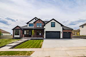 Modern inspired farmhouse with a porch, board and batten siding, driveway, brick siding, and a garage