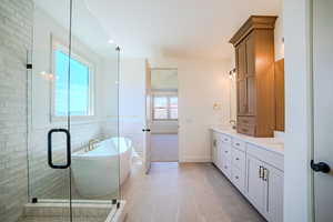 Bathroom featuring double vanity, a freestanding bath, a shower stall, and light tile patterned floors