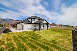Back of house with a fenced backyard, a shingled roof, a patio area, and a mountain view