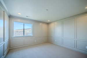 Empty room featuring a decorative wall, recessed lighting, light carpet, and a textured ceiling
