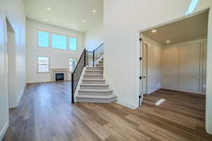 Staircase with a high ceiling, recessed lighting, a glass covered fireplace, and hardwood / wood-style flooring