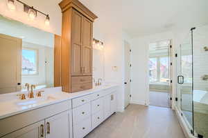 Bathroom with double vanity, a stall shower, and light tile patterned floors