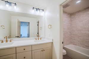 Bathroom featuring double vanity, shower / tub combination, and recessed lighting