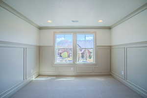 Unfurnished room with a decorative wall, wainscoting, a textured ceiling, carpet flooring, and a mountain view