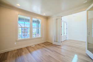Empty room with light wood-style flooring, ornamental molding, french doors, and recessed lighting