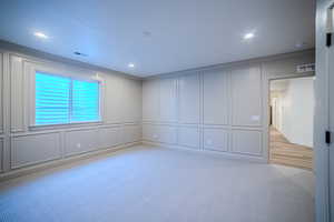 Unfurnished room with a decorative wall, light colored carpet, and recessed lighting
