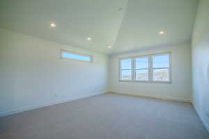 Carpeted empty room with healthy amount of natural light, recessed lighting, and lofted ceiling