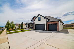 View of front of home featuring brick siding, concrete driveway, board and batten siding, an attached garage, and a front lawn