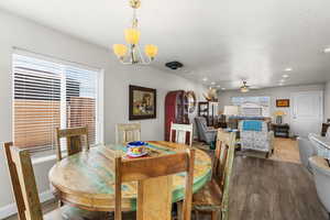 Dining space with dark wood-type flooring, a chandelier, ceiling fan, and arched walkways