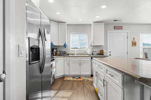 Kitchen featuring stainless steel appliances, white cabinets, a textured ceiling, dark wood-style floors, and recessed lighting