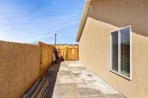 View of property exterior with a fenced backyard, stucco siding, a gate, and a patio