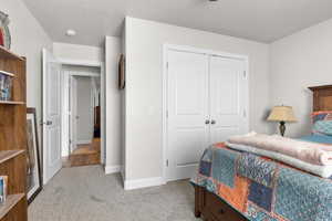 Bedroom with light carpet, a closet, and a textured ceiling