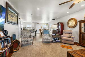 Living area with hanging lights, a ceiling fan, and light carpet