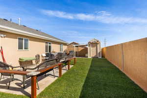 Fenced backyard featuring a shed and a patio area