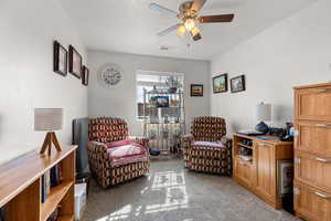 Living area with a ceiling fan, light carpet, and a textured ceiling