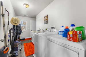 Laundry area with dark wood finished floors, separate washer and dryer, a textured ceiling, and cabinet space