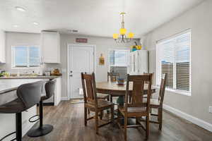 Dining space with dark wood-style floors, a textured ceiling, and hanging lights