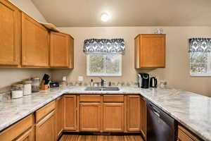 Kitchen featuring wood finish cabinets, stainless steel dishwasher, light countertops, and a textured ceiling