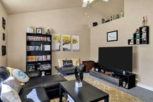 Carpeted living area with lofted ceiling and ceiling fan