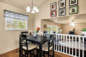 Dining space with vaulted ceiling, a chandelier, wood finished floors, and ceiling fan