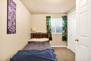 Carpeted bedroom featuring a textured ceiling and a closet