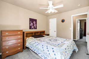 Carpeted bedroom featuring a ceiling fan and a textured ceiling